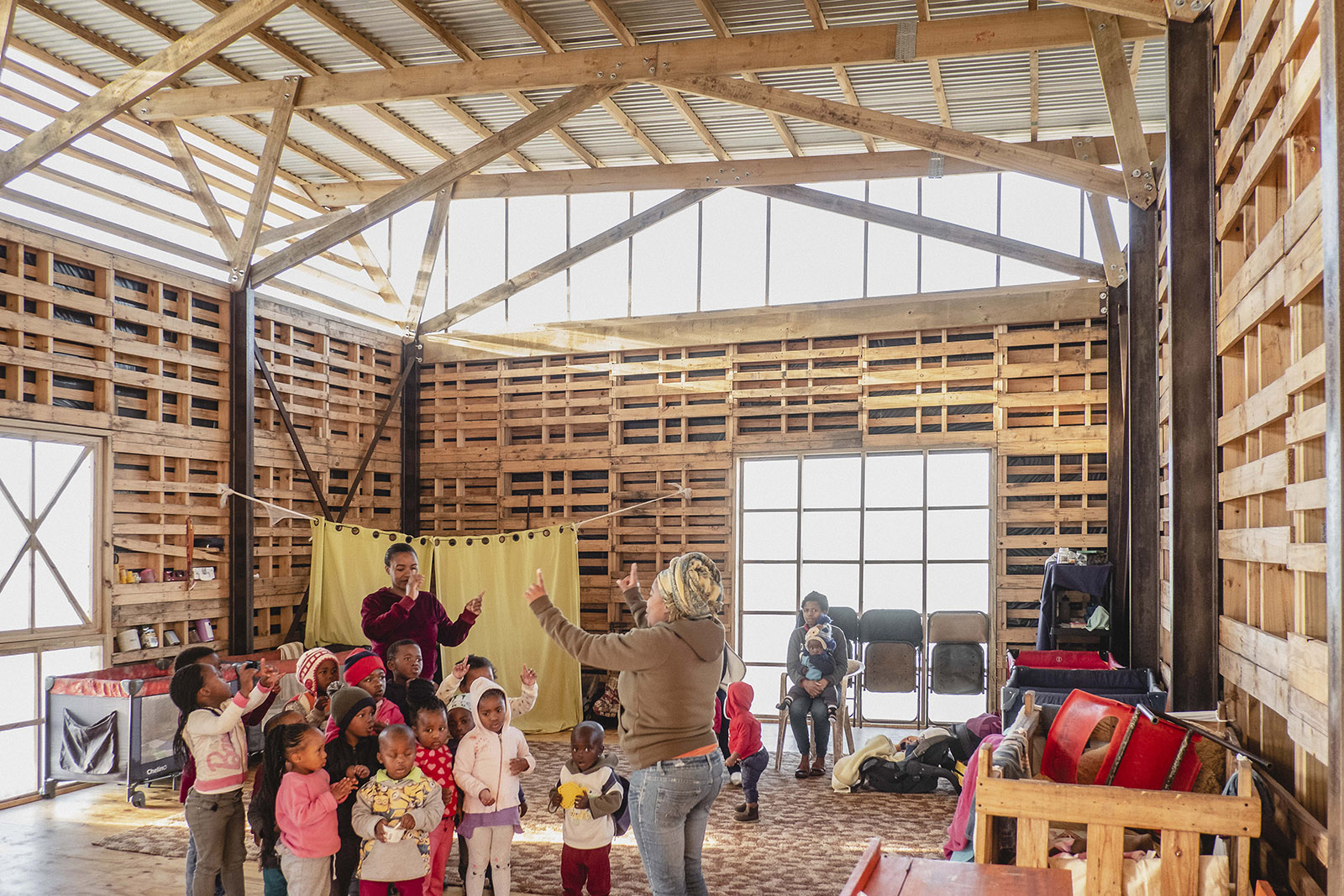 The crèche seen from the inside shows that timber pallets have been used to make the walls, with a corrugated plastic strip below the roof to introduce daylight