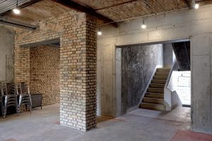 The concrete stair core with a beautifully curved balustrade can be seen from the masonry offices of Farsh Film Studio