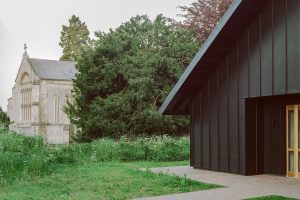 Castle Community Room's porch entrance, seen right, with the church in the background at left. The community rooms are clad in black zinc