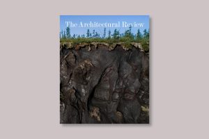 The Architectural Review Ground issue cover, September 2024, depicts a crater in Siberia formed from the collapse of melting permafrost. The photograph is by Katie Orlinsky and features a blue sky in the top 20%, then trees, grass and dark brown mud in gooey forms in the bottom two thirds of the image
