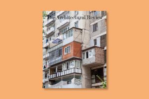 The cover of The Architectural Review’s February 2025 issue, Extensions, on a yellow background. the cover depicts a cluster of varied, self-built extensions to a housing block