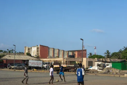 A group of children playing football in the paved over forecourt of the Accra Community Centre