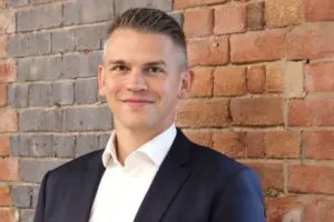 Headshot of Martin Staehr, Group managing director of Kier’s Construction business, standing against a brick wall